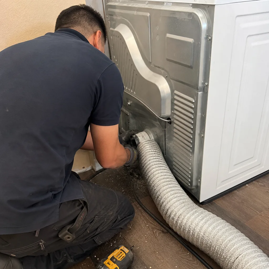 Technician installing flexible dryer vent hose on back of dryer unit